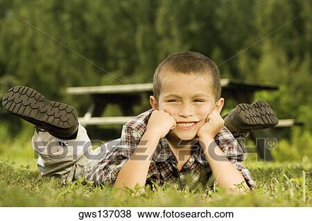 Close-up of a boy lying on the lawn View Large Photo Image Stock Photo - Close-up of a boy lying on the lawn. Fotosearch