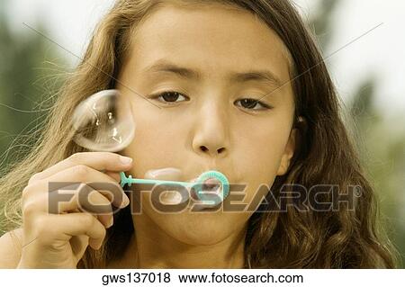 Stock Photo - Close-up of a girl blowing bubbles with a bubble wand. Fotosearch