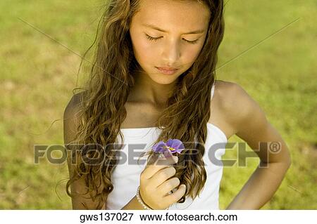 Close-up of a girl holding a flower View Large Photo Image Stock Photo - Close-up of a girl holding a flower. Fotosearch