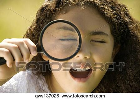 Close-up of a girl looking through a magnifying glass View Large Photo Image Stock Photograph - Close-up of a girl looking through a magnifying glass. Fotosearch
