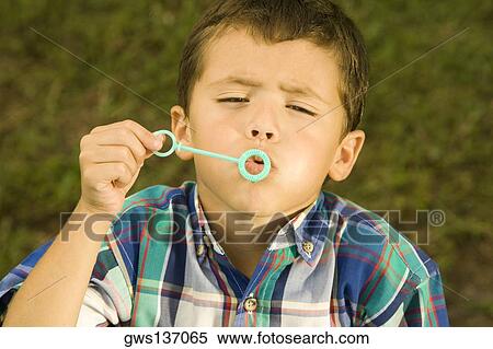 Stock Photography - High angle view of a boy blowing bubbles with a bubble wand. Fotosearch
