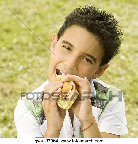 Portrait of a boy eating a burger View Large Photo Image Picture - Portrait of a boy eating a burger. Fotosearch