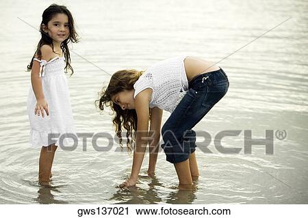 Stock Image - Portrait of a girl and her sister standing in a river. Fotosearch