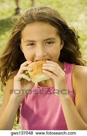 Portrait of a girl eating a burger View Large Photo Image Stock Photo - Portrait of a girl eating a burger. Fotosearch