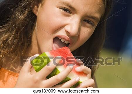 Portrait of a girl eating a slice of a watermelon View Large Photo Image Stock Photo - Portrait of a girl eating a slice of a watermelon. Fotosearch