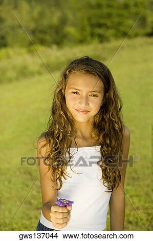 Portrait of a girl holding a flower View Large Photo Image Picture - Portrait of a girl holding a flower. Fotosearch
