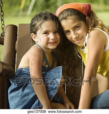 Portrait of two sisters sitting on a swing View Large Photo Image Stock Photo - Portrait of two sisters sitting on a swing. Fotosearch