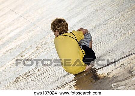 Rear view of a boy squatting on the beach View Large Photo Image Picture - Rear view of a boy squatting on the beach. Fotosearch
