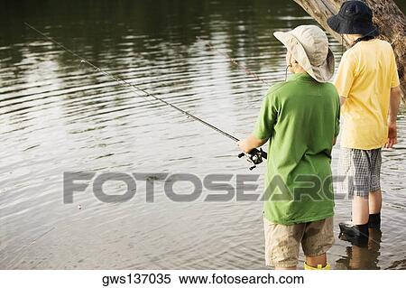 Rear view of two brothers fishing near a lake View Large Photo Image Stock Photography - Rear view of two brothers fishing near a lake. Fotosearch
