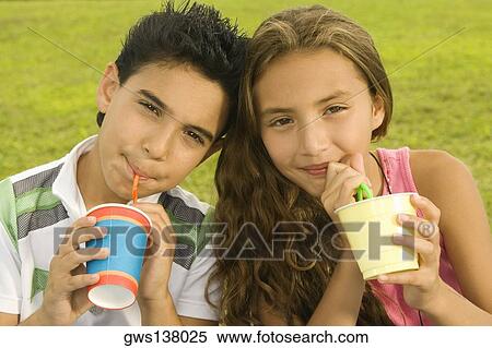 Stock Photography - Close-up of a boy and a girl drinking with drinking straws. Fotosearch