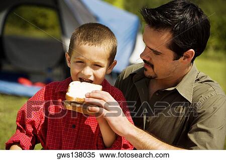 Close-up of a boy eating a sandwich with his father View Large Photo Image Stock Photography - Close-up of a boy eating a sandwich with his father. Fotosearch