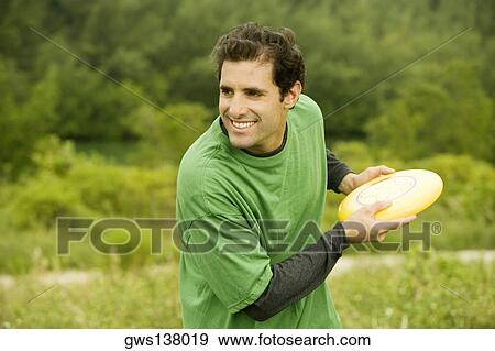 Close-up of a mid adult man throwing a plastic disc View Large Photo Image Stock Photo - Close-up of a mid adult man throwing a plastic disc. Fotosearch