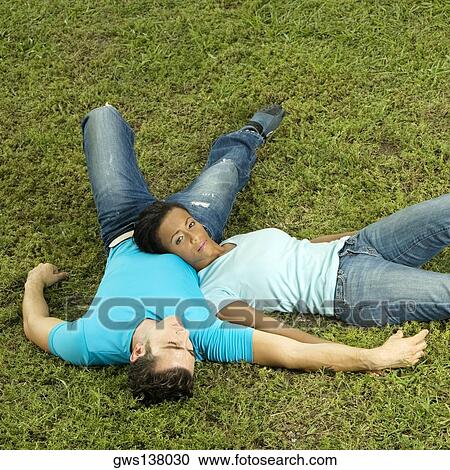 High angle view of a young couple lying on the grass View Large Photo Image Stock Image - High angle view of a young couple lying on the grass. Fotosearch