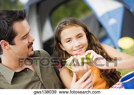 Portrait of a girl holding a watermelon with her father looking at her View Large Photo Image Stock Photo - Portrait of a girl holding a watermelon with her father looking at her. Fotosearch