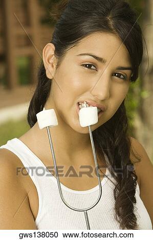 Stock Image - Portrait of a teenage girl eating marshmallow. Fotosearch