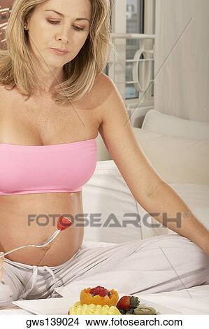 Close-up of a pregnant woman holding a strawberry on a fork View Large Photo Image Picture - Close-up of a pregnant woman holding a strawberry on a fork. Fotosearch