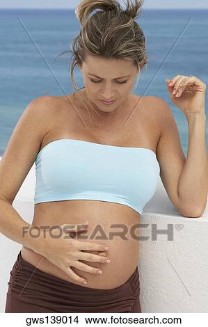 Close-up of a pregnant woman touching her abdomen View Large Photo Image Picture - Close-up of a pregnant woman touching her abdomen. Fotosearch