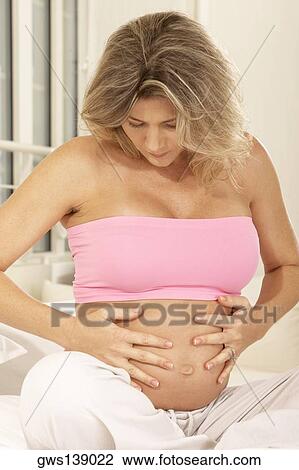 Close-up of a pregnant woman touching her abdomen View Large Photo Image Stock Image - Close-up of a pregnant woman touching her abdomen. Fotosearch