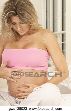 Close-up of a pregnant woman touching her abdomen View Large Photo Image Stock Image - Close-up of a pregnant woman touching her abdomen. Fotosearch