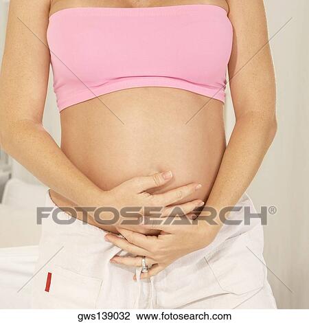 Mid section view of a pregnant woman touching her abdomen View Large Photo Image Stock Image - Mid section view of a pregnant woman touching her abdomen. Fotosearch