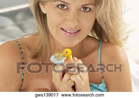 Stock Photo - Portrait of a pregnant woman holding two pacifiers. Fotosearch