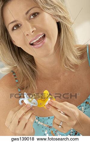 Stock Photo - Portrait of a pregnant woman holding two pacifiers. Fotosearch
