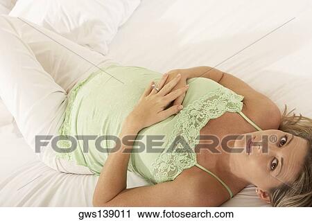 Stock Image - Portrait of a pregnant woman lying on the bed. Fotosearch