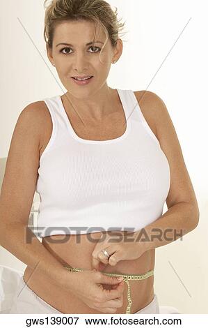 Portrait of a pregnant woman measuring her abdomen with a measuring tape View Large Photo Image Stock Photo - Portrait of a pregnant woman measuring her abdomen with a measuring tape. Fotosearch