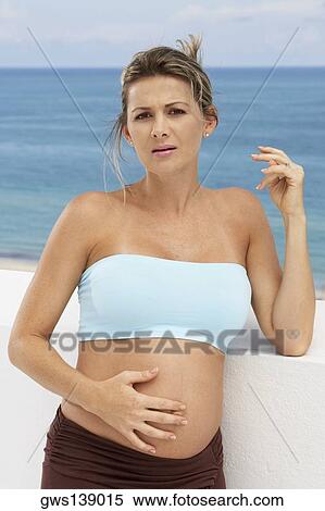 Stock Photography - Portrait of a pregnant woman touching her abdomen. Fotosearch