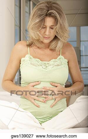 Pregnant mid adult woman touching her abdomen View Large Photo Image Stock Photo - Pregnant mid adult woman touching her abdomen. Fotosearch