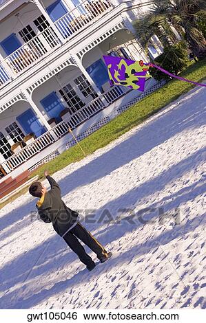 Rear view of a boy flying a kite View Large Photo Image Stock Photograph - Rear view of a boy flying a kite. Fotosearch