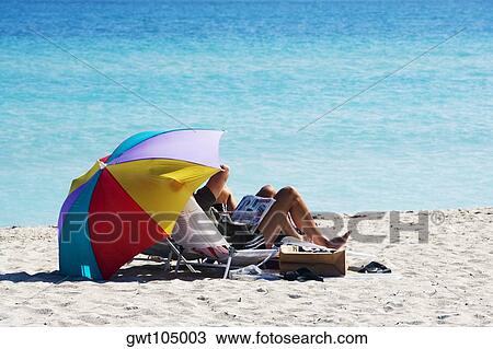 Two people under a beach umbrella, Miami, Florida, USA View Large Photo Image Stock Image - Two people under a beach umbrella, Miami, Florida, USA. Fotosearch