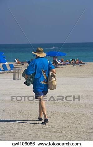 Stock Photograph - Rear view of a man walking on the beach, South Beach, Miami, Florida, USA. Fotosearch