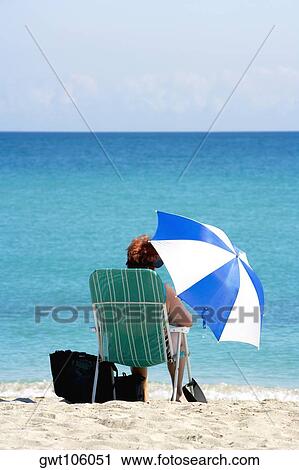 Rear view of a woman sitting on the beach, South Beach, Miami, Florida, USA View Large Photo Image Stock Image - Rear view of a woman sitting on the beach, South Beach, Miami, Florida, USA. Fotosearch