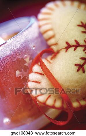 Stock Image - Close-up of a lit candle and a heart shaped cushion. Fotosearch