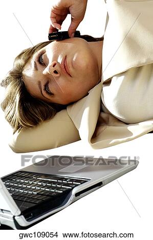 Picture - Close-up of a businesswoman talking on a mobile phone in front of a laptop. Fotosearch