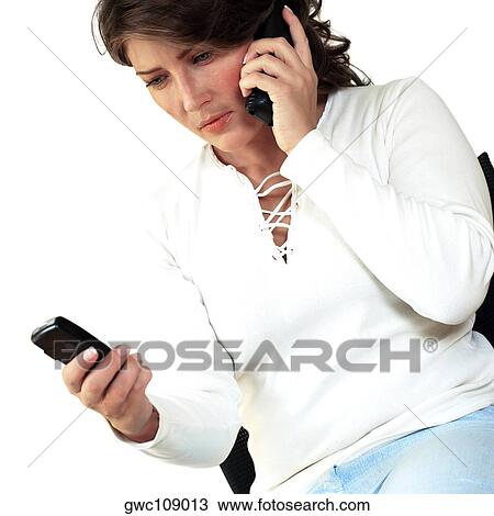 Stock Image - Close-up of a businesswoman using two mobile phones. Fotosearch