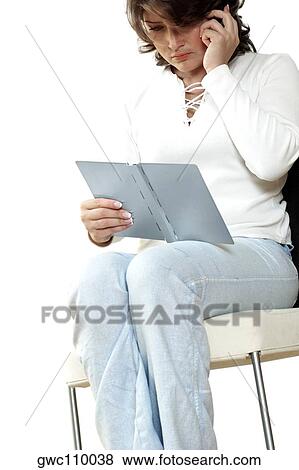 Stock Photo - Businesswoman talking on a mobile phone and reading a diary. Fotosearch