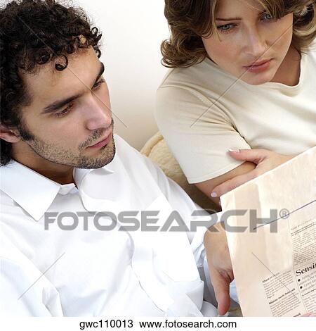 Stock Image - High angle view of a young couple reading a newspaper. Fotosearch