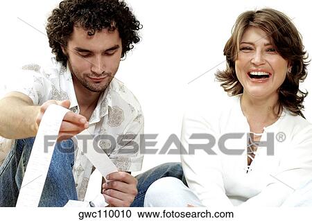 Stock Image - Portrait of a young woman laughing with a young man looking at a receipt. Fotosearch