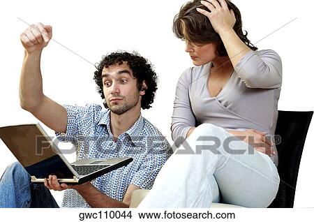 Young couple looking at a laptop View Large Photo Image Picture - Young couple looking at a laptop. Fotosearch