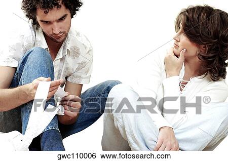 Stock Photograph - Young man sitting with a young woman holding a receipt. Fotosearch