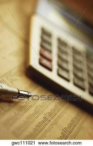 Stock Image - Close-up of a pen and a calculator on a financial newspaper. Fotosearch