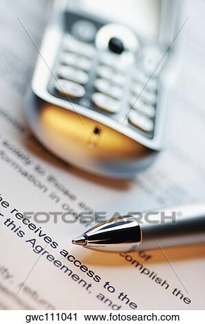 Stock Image - Close-up of a pen and a mobile phone on a document. Fotosearch