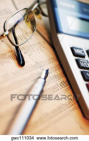 Picture - Close-up of a pen with eyeglasses and a calculator on a financial newspaper. Fotosearch