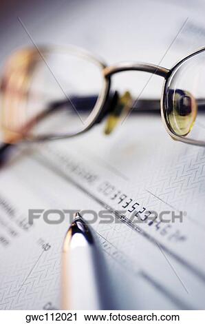 Stock Image - Pen and eyeglasses on a check. Fotosearch