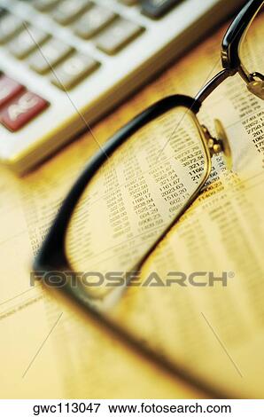 Stock Photo - Close-up of eyeglasses and a calculator on a financial newspaper. Fotosearch