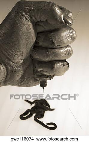 Picture - Close-up of a person's hand squeezing a paint tube. Fotosearch