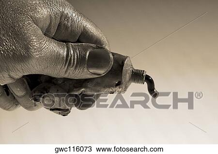 Stock Image - Close-up of a person's hand squeezing a paint tube. Fotosearch