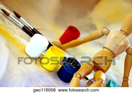 Wooden figurine sitting on bottles of paint View Large Photo Image Stock Photo - Wooden figurine sitting on bottles of paint. Fotosearch